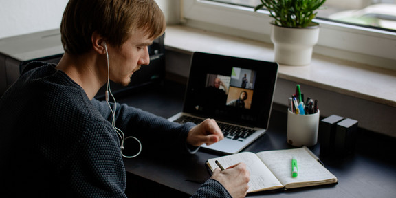 A student works with a laptop and notebook.